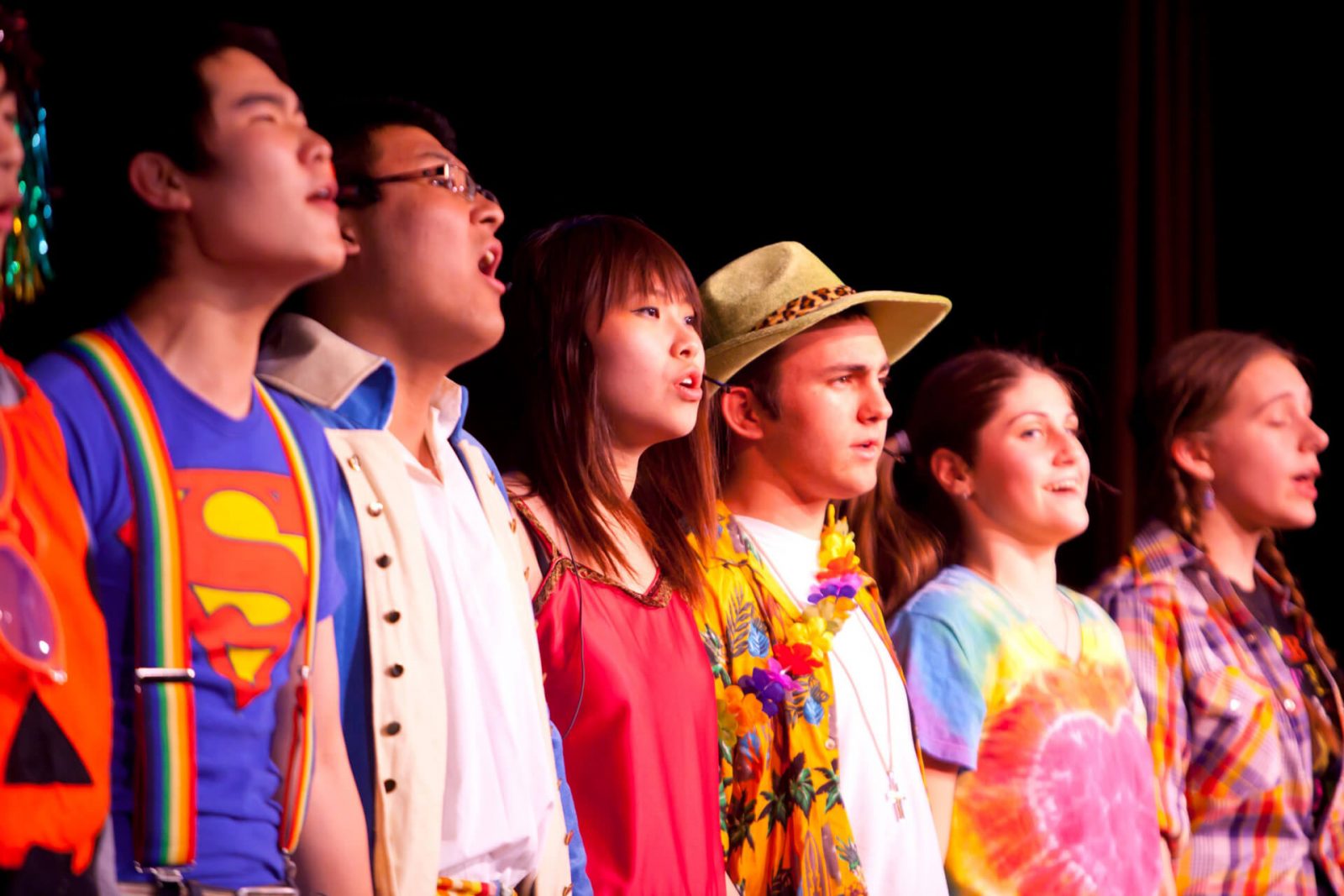 seis estudiantes de orígenes diversos, cantan sobre un escenario