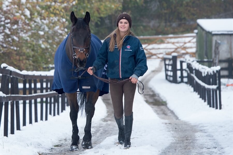 chica caminando al lado de un caballo