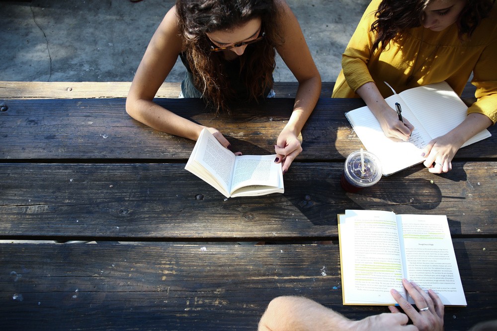 chicas estudiando alrededor de mesa de madera